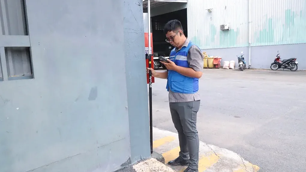 Cán bộ đo đạc cầm thiết bị kiểm đếm đất và tài sản của người dân thuộc dự án metro tại Bình Dương