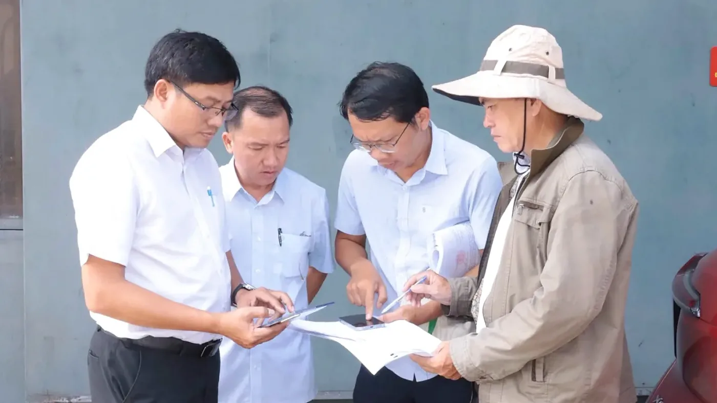 Cán bộ phường xem bản vẽ và thiết bị khi đo đạc, kiểm đếm đất dự án metro tại Bình Dương