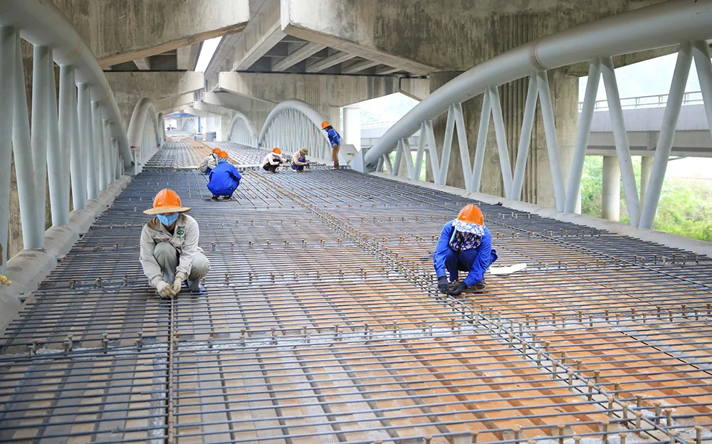 Công nhân đội mũ bảo hộ buộc thép trên mặt cầu tại công trường tuyến metro