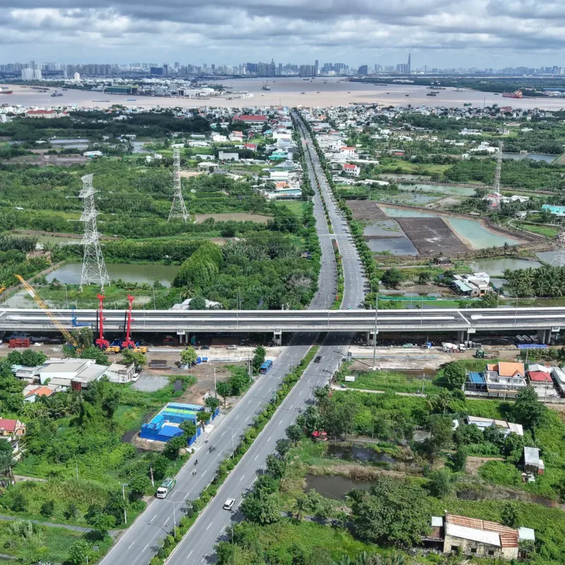 Cầu vượt lớn đang hoàn thiện bắc ngang trục đường đô thị, nhìn từ trên cao với các khu dân cư hai bên