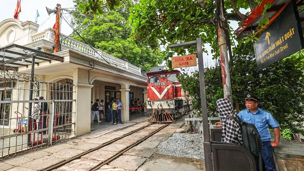 Đoàn tàu đỏ vào ga Gia Lâm ở Hà Nội, đường ray sát nhà ga và biển chỉ đường Trần Nhật Duật