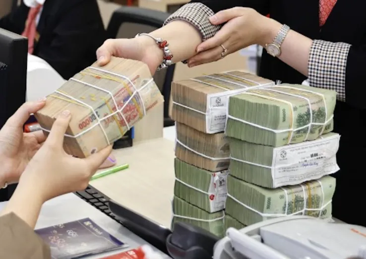 Nhân viên ngân hàng trao các bó tiền mặt cho khách tại quầy giao dịch, minh hoạ khoản vay mua nhà