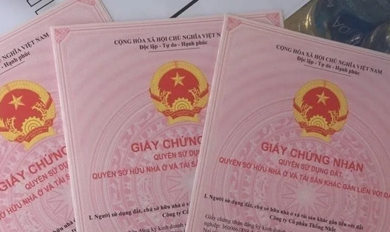 Ba cuốn giấy chứng nhận quyền sử dụng đất, quyền sở hữu nhà ở màu hồng đặt cạnh nhau