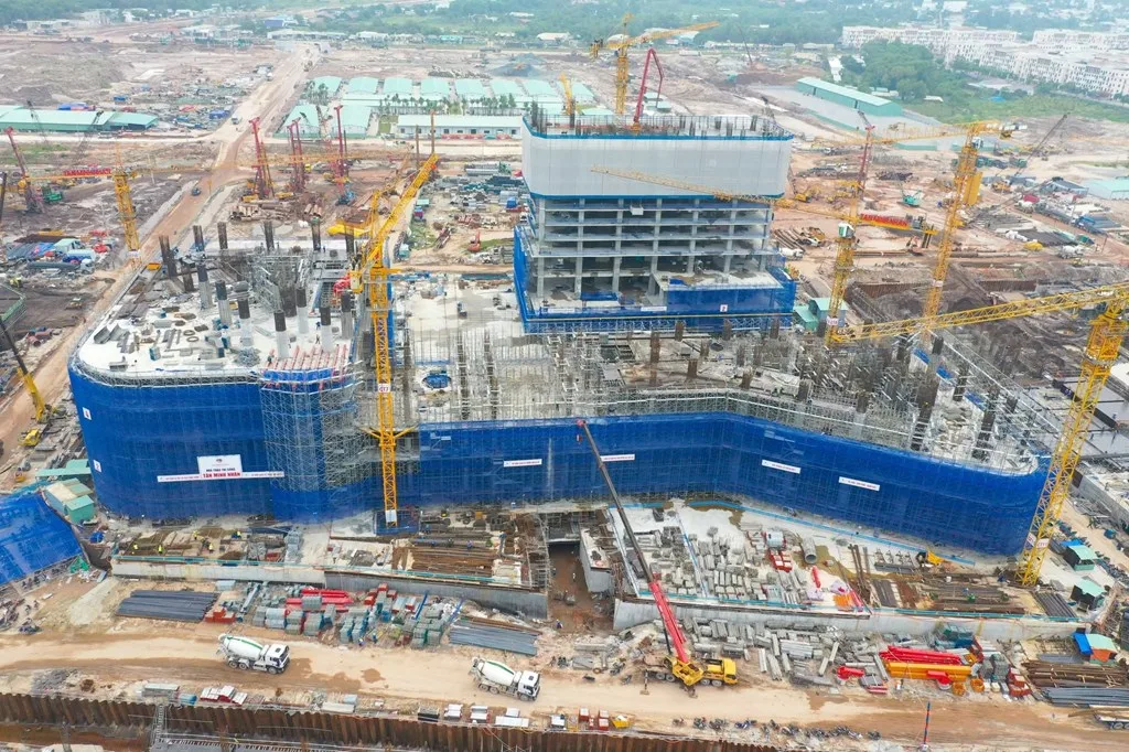 Ảnh thực tế một tòa khách sạn cao tầng đang thi công với lớp bạt xanh và nhiều cần trục tại Ruby Beach, Phú Quốc