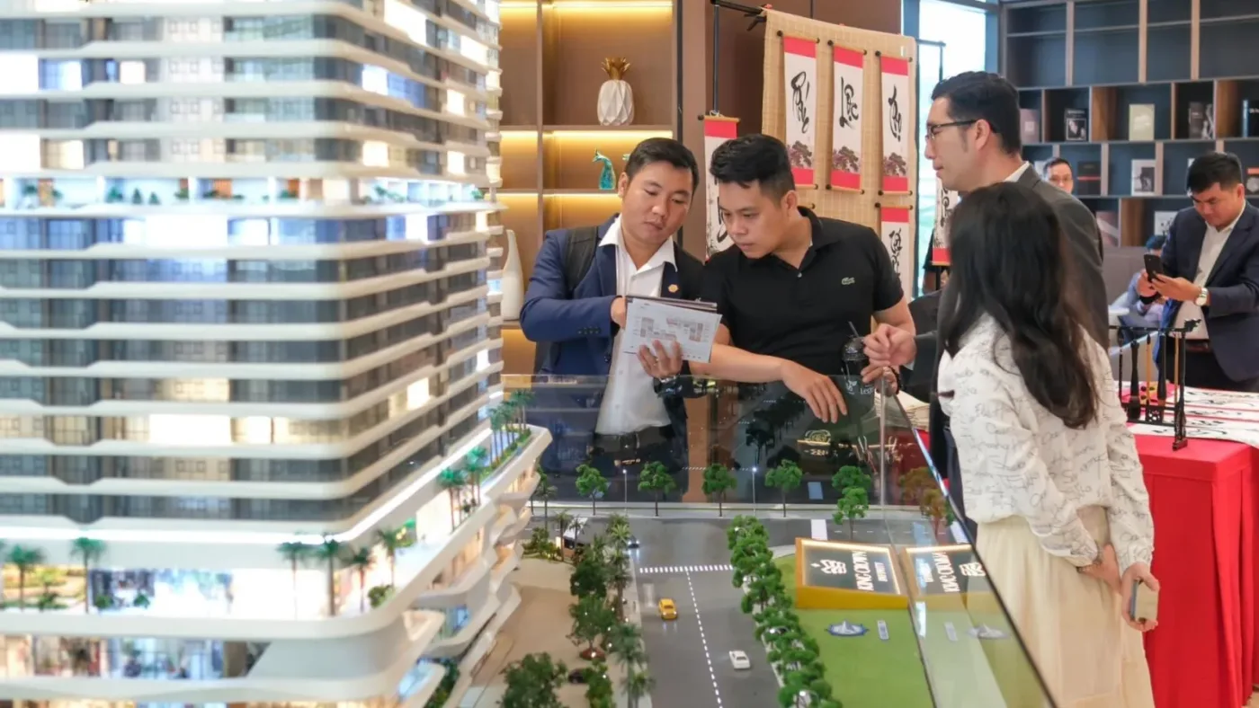 Khách hàng xem mô hình dự án căn hộ cùng nhân viên tư vấn tại khu vực mở bán, minh hoạ nguồn cung mới và tiêu thụ giảm