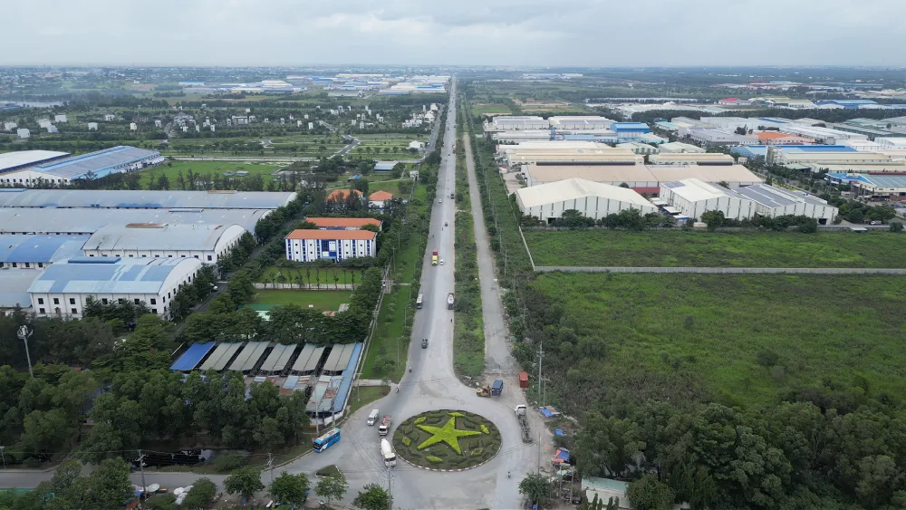 Toàn cảnh khu công nghiệp với nhà xưởng hai bên đường và nhiều khoảng đất trống chưa lấp đầy