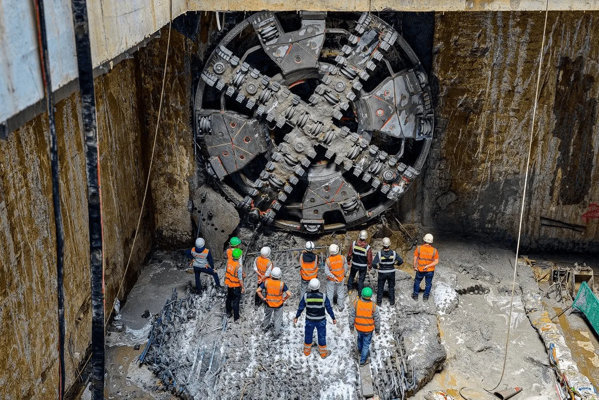 Công nhân đứng trước mũi khoan máy đào hầm TBM trong hố thi công ngầm metro