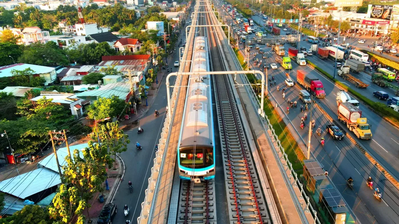 Đoàn tàu Metro số 1 chạy trên cao dọc Xa lộ Hà Nội, hai bên là khu dân cư và đường xe cộ
