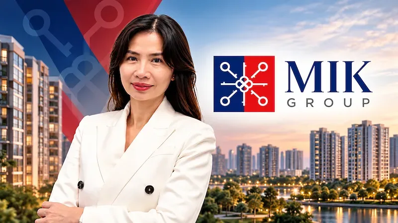 Chân dung nữ lãnh đạo mặc vest trắng bên logo MIK Group và khu căn hộ cao tầng lúc hoàng hôn