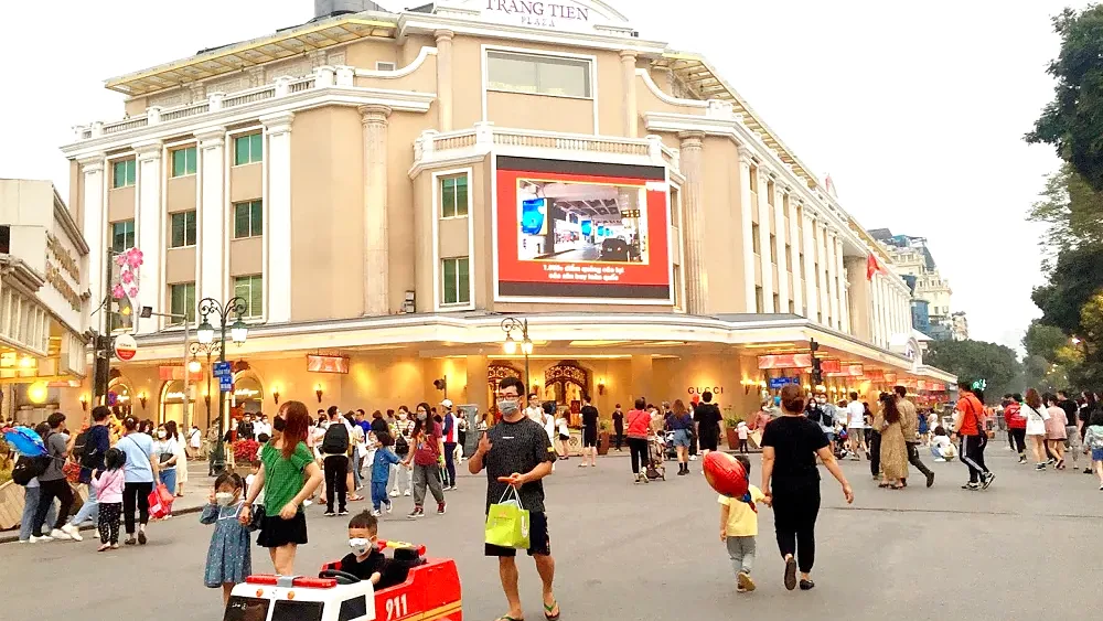 Người dân đi bộ trên phố quanh hồ Hoàn Kiếm, phía sau là tòa nhà Tràng Tiền Plaza