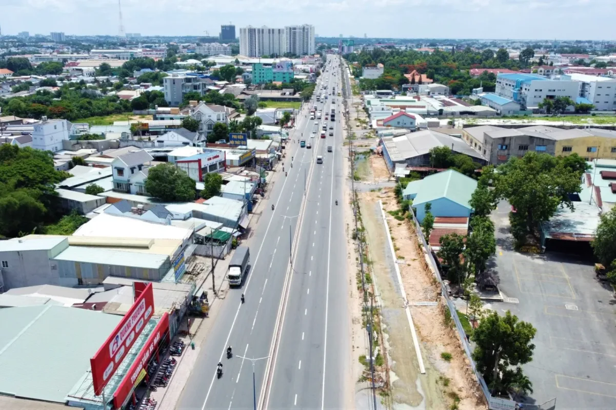 Quốc lộ 13 nhìn từ trên cao với xe cộ lưu thông, hai bên là nhà dân và nhà xưởng