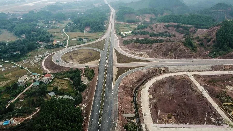 Toàn cảnh tuyến cao tốc và nút giao nhìn từ trên cao giữa vùng đồi núi, minh hoạ cao tốc long an - Tây Ninh
