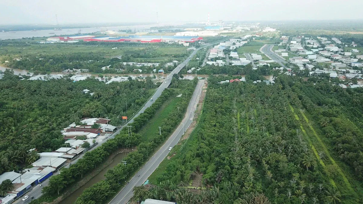 Toàn cảnh tuyến đường chạy qua vùng đồng bằng nhiều cây xanh, nhà dân và khu công nghiệp ven sông