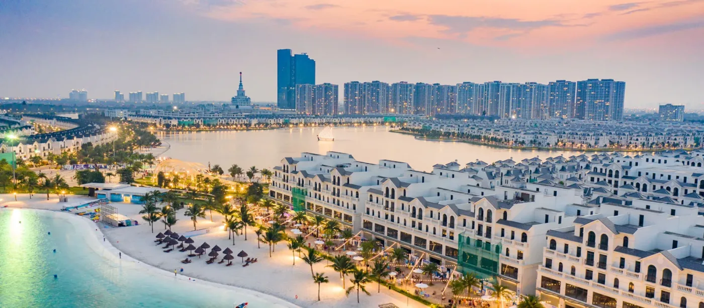 Phối cảnh Vinhomes Ocean Park với hồ nước lớn, bãi cát ven hồ, dãy nhà liền kề và các toà cao tầng phía xa