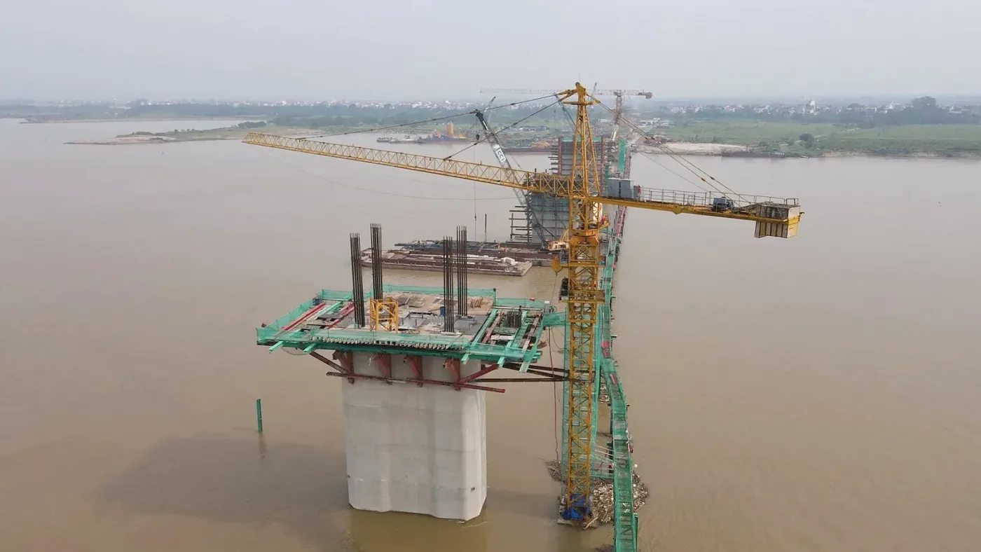 Trụ cầu Hồng Hà đang thi công giữa sông Hồng với cần cẩu tháp và giàn khuôn thép, thuộc Vành đai 4