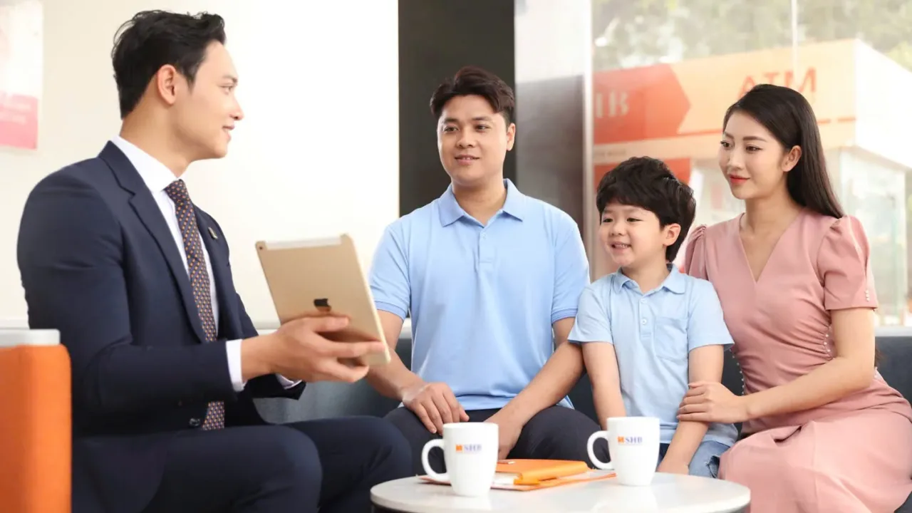 Nhân viên ngân hàng tư vấn khoản vay mua nhà cho gia đình ba người tại quầy giao dịch